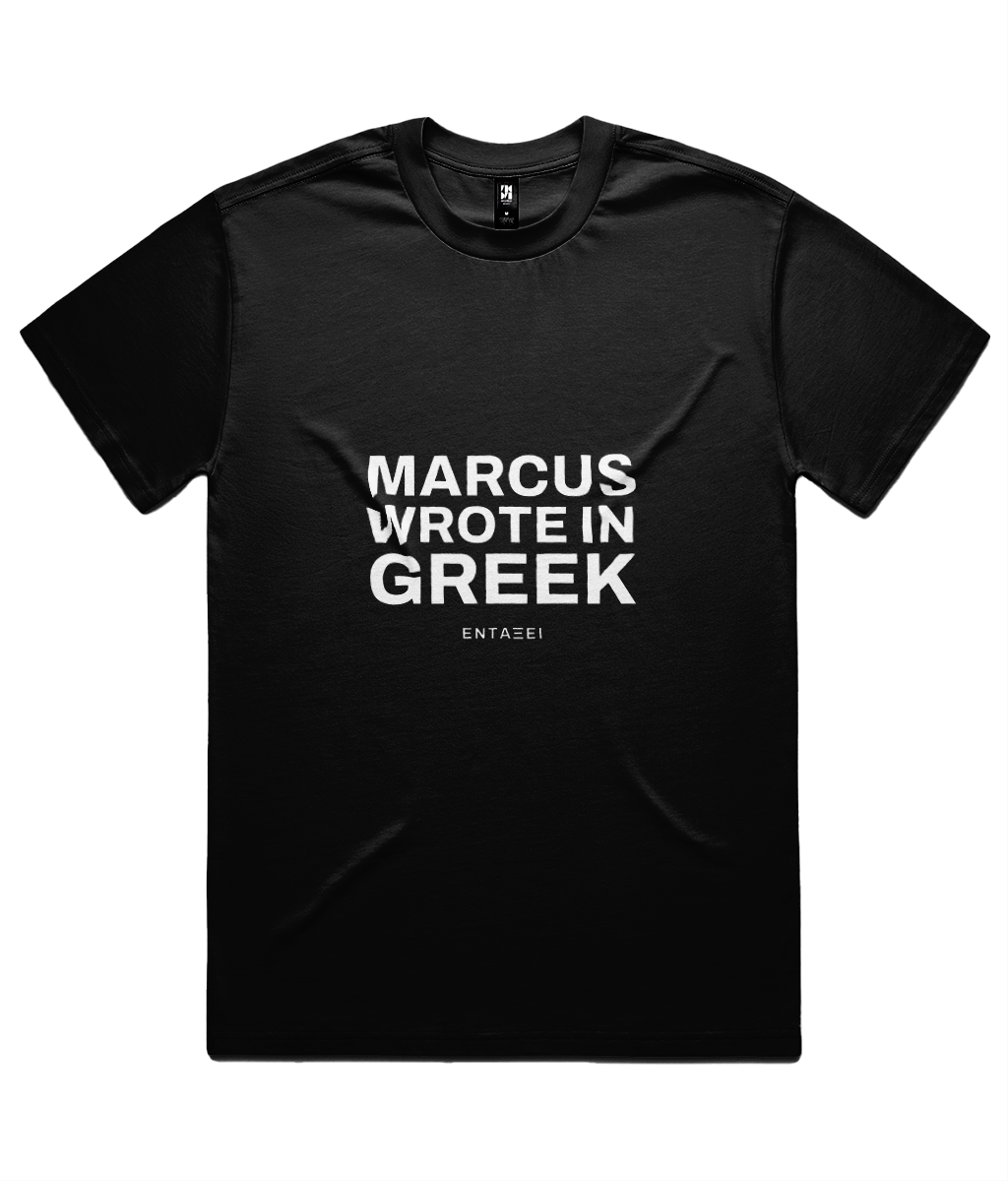 Black Marcus Wrote In Greek Tee shown flat on white, front print: MARCUS WROTE IN GREEK in three lines of heavy sans capitals with the ΕΝΤΑΞΕΙ wordmark beneath.