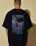 Model seen from behind wearing the black Citium Tee, shipwreck and spilled purple dye printed across the back